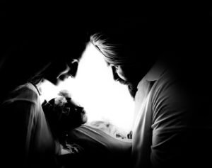 Dramatic black and white newborn photography of parents holding their sleeping baby in beautiful silhouette light