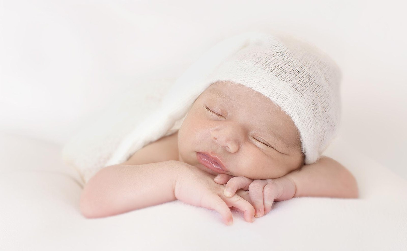 Newborn baby posing with hands under chin on soft background – Surrey newborn photographer