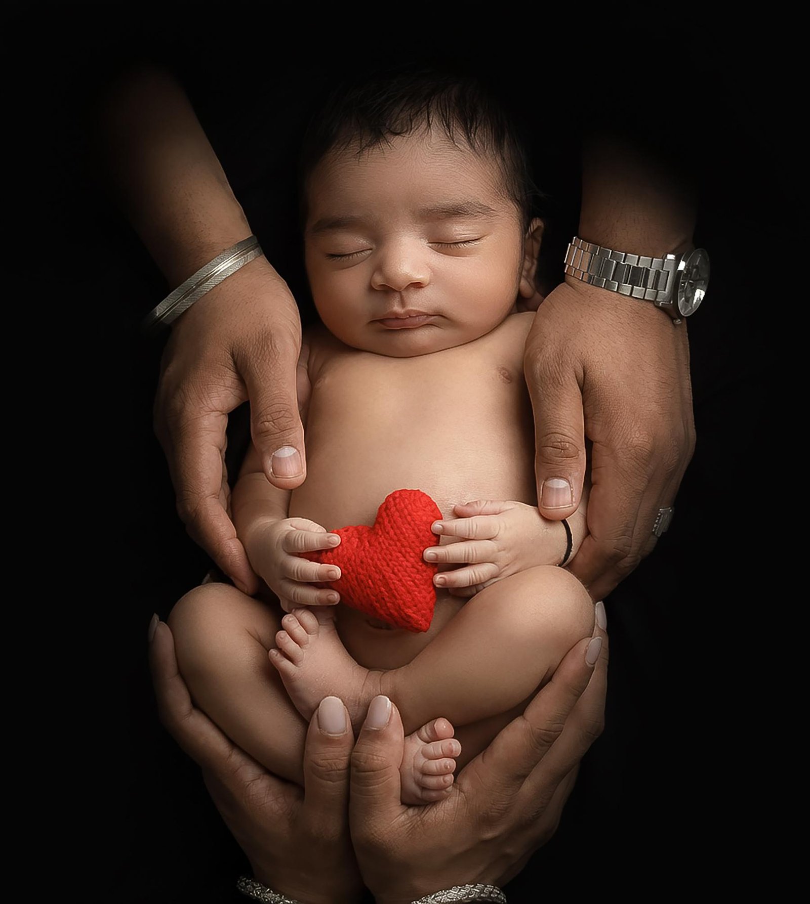 Newborn baby held in hands with red heart prop – Surrey newborn photographer