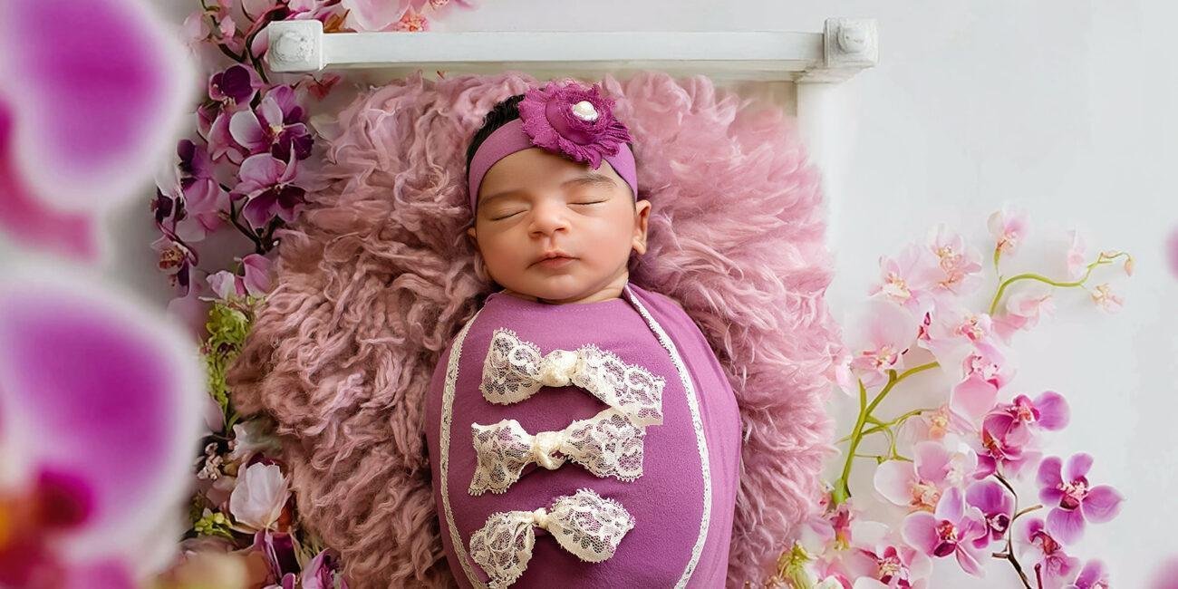 Newborn baby in purple floral setup with delicate flowers – London newborn photographer
