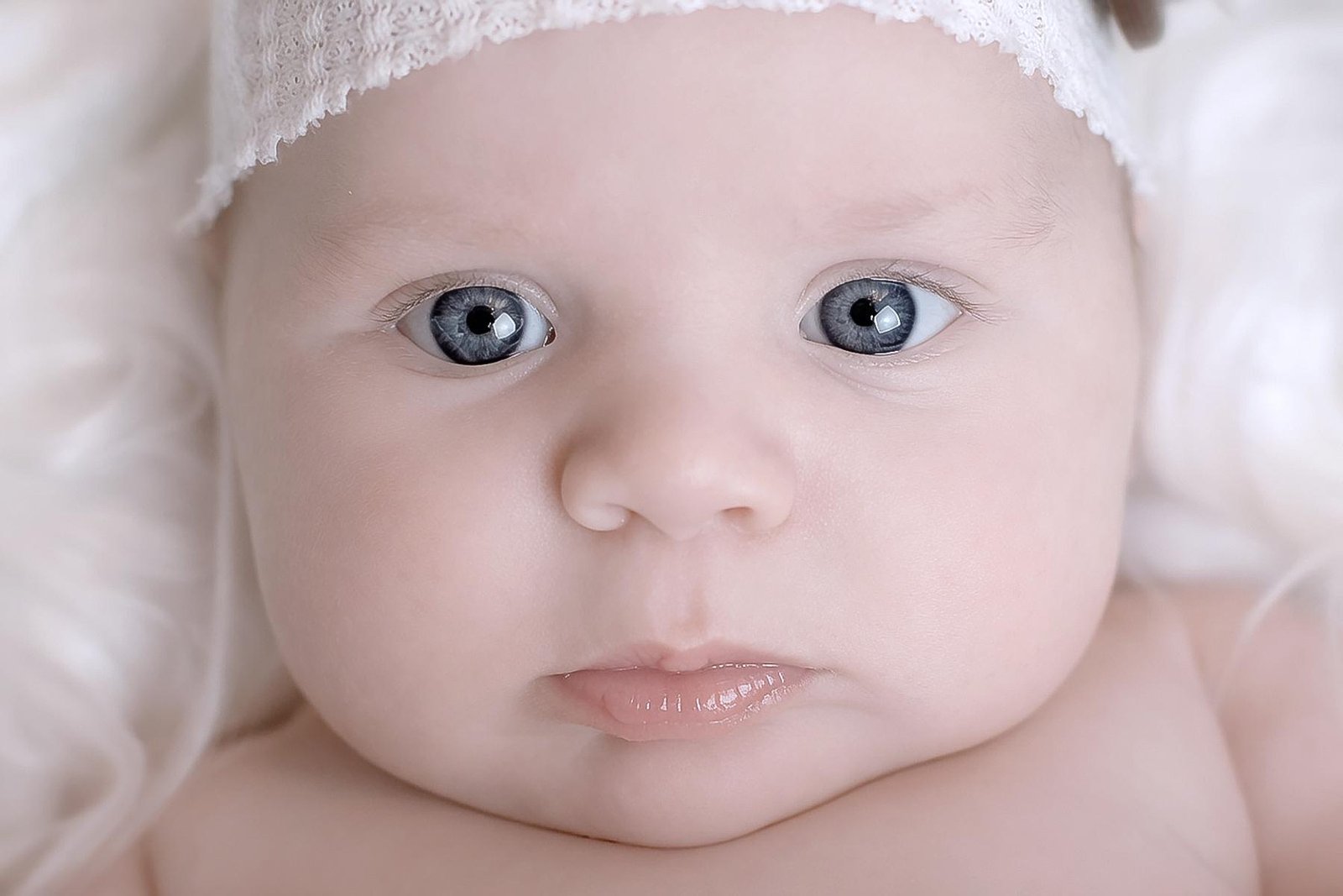 This close-up newborn portrait features a baby boy with striking blue eyes and soft, natural tones.