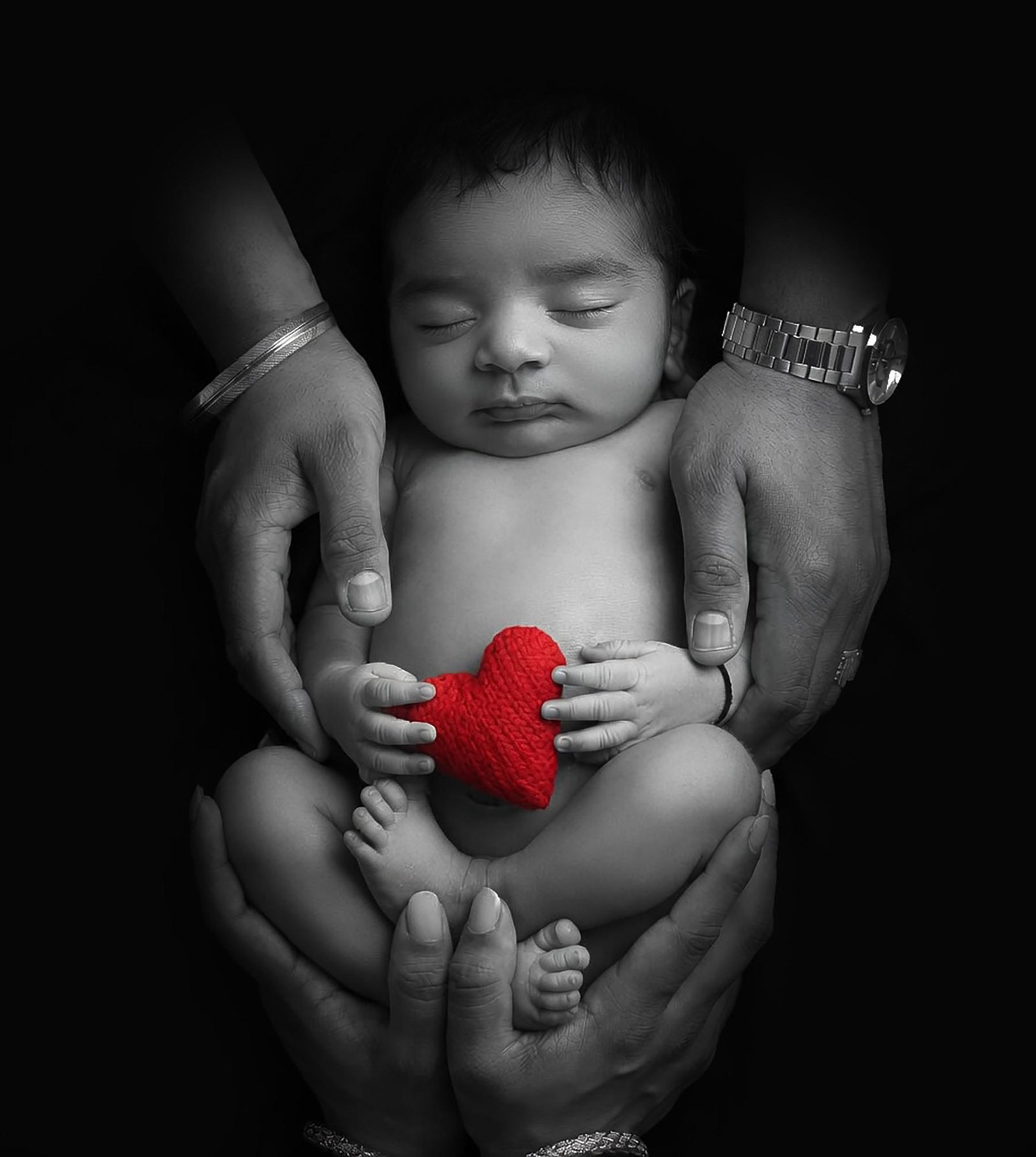 Black and white newborn portrait holding red heart prop – London newborn photographer