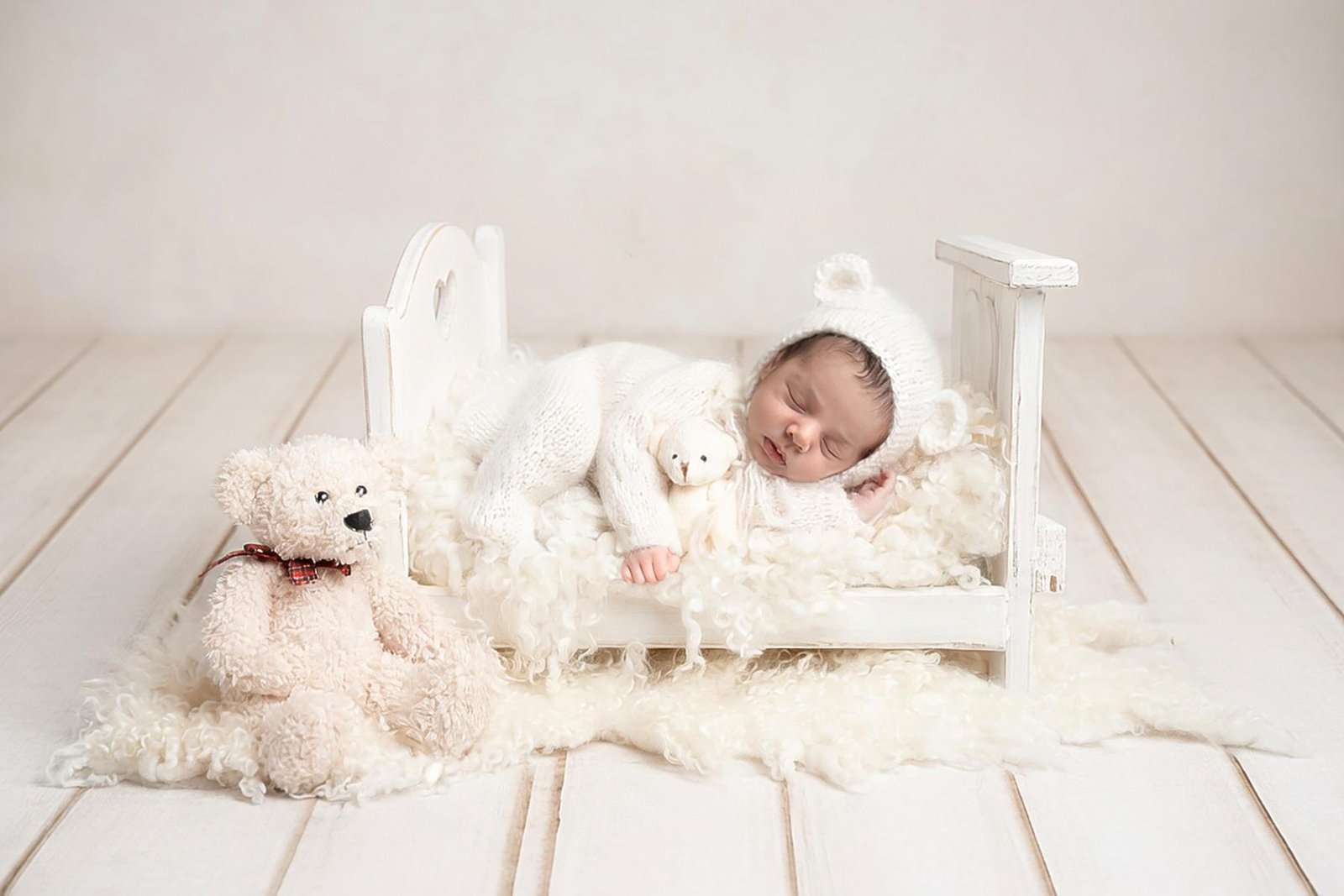 Newborn baby lying on bed with soft neutral styling and props – Surrey newborn photographer