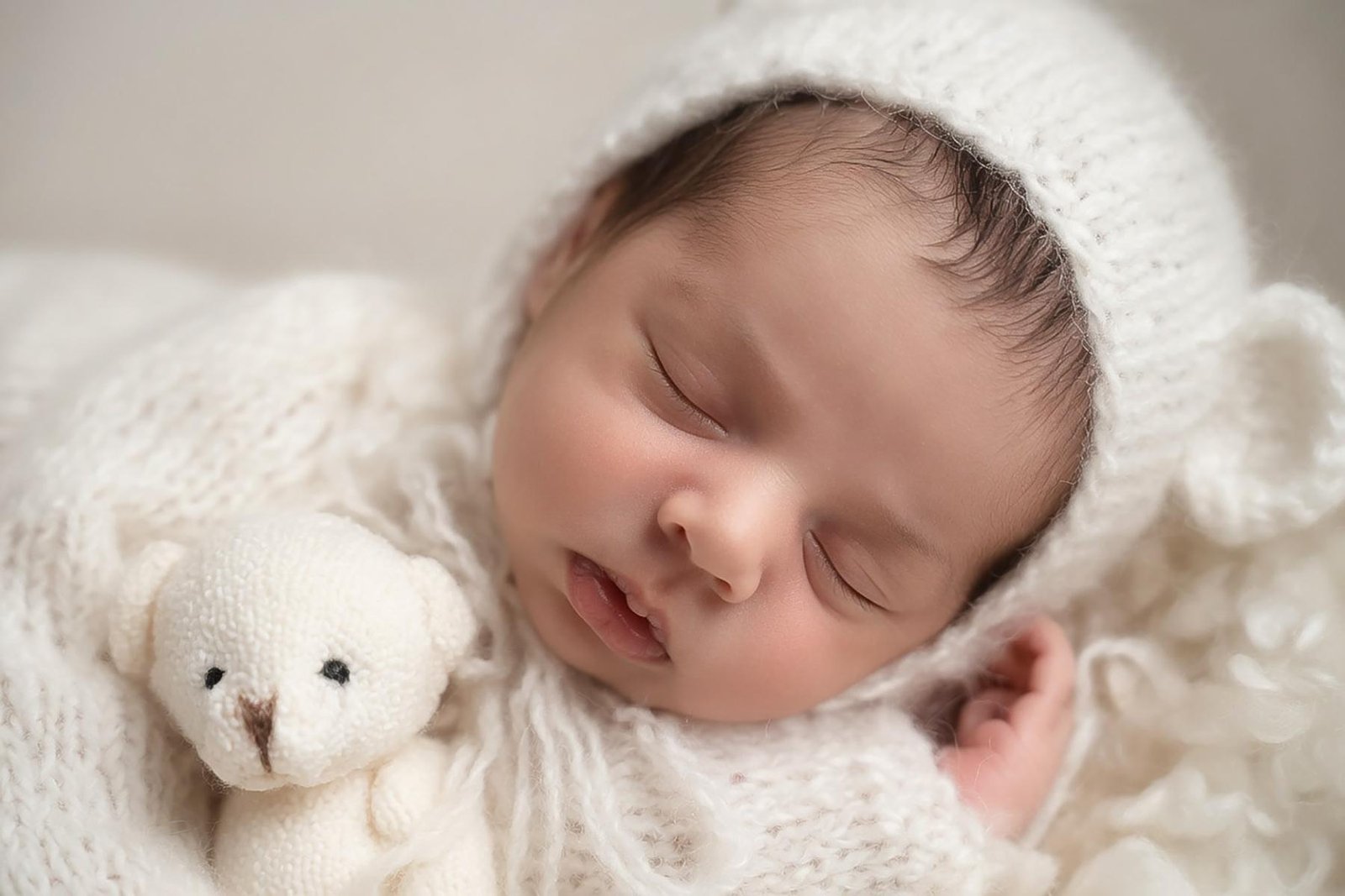 Newborn baby sleeping beside teddy bear with soft neutral tones – Surrey newborn photographer
