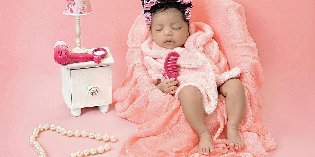 Newborn baby girl in pink spa day setup with curlers in hair – London newborn photographer
